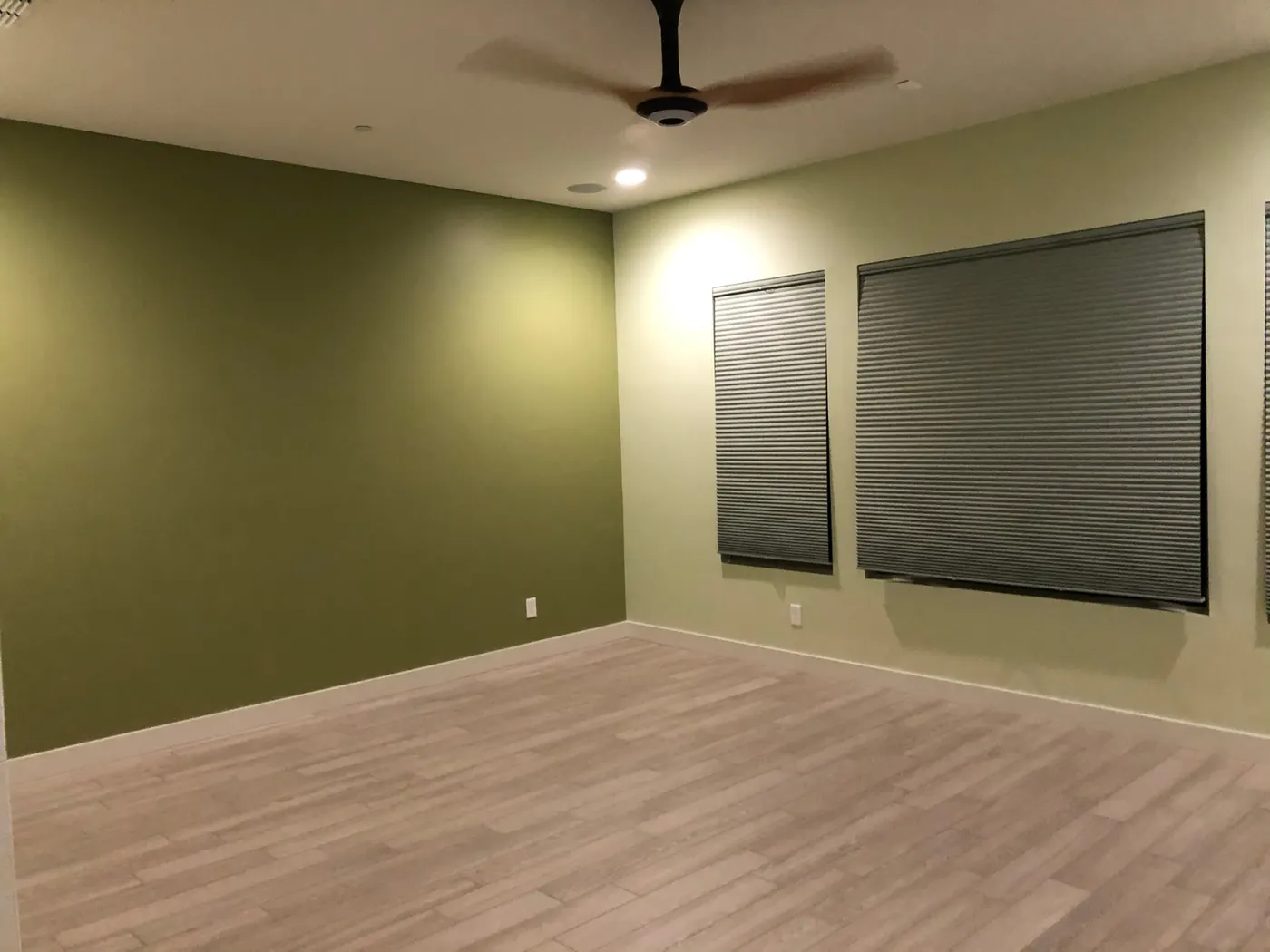 Finished bedroom with olive green accent wall and soft green surrounding walls