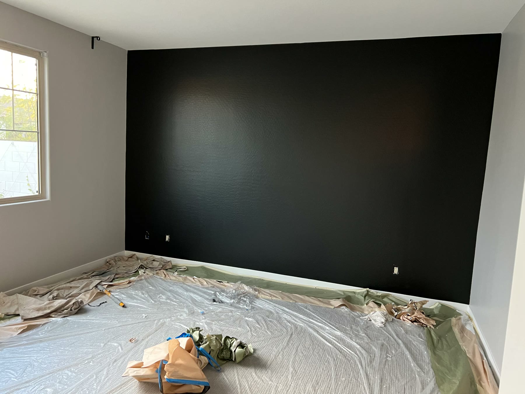 Interior room with a finished matte black accent wall and floors masked off